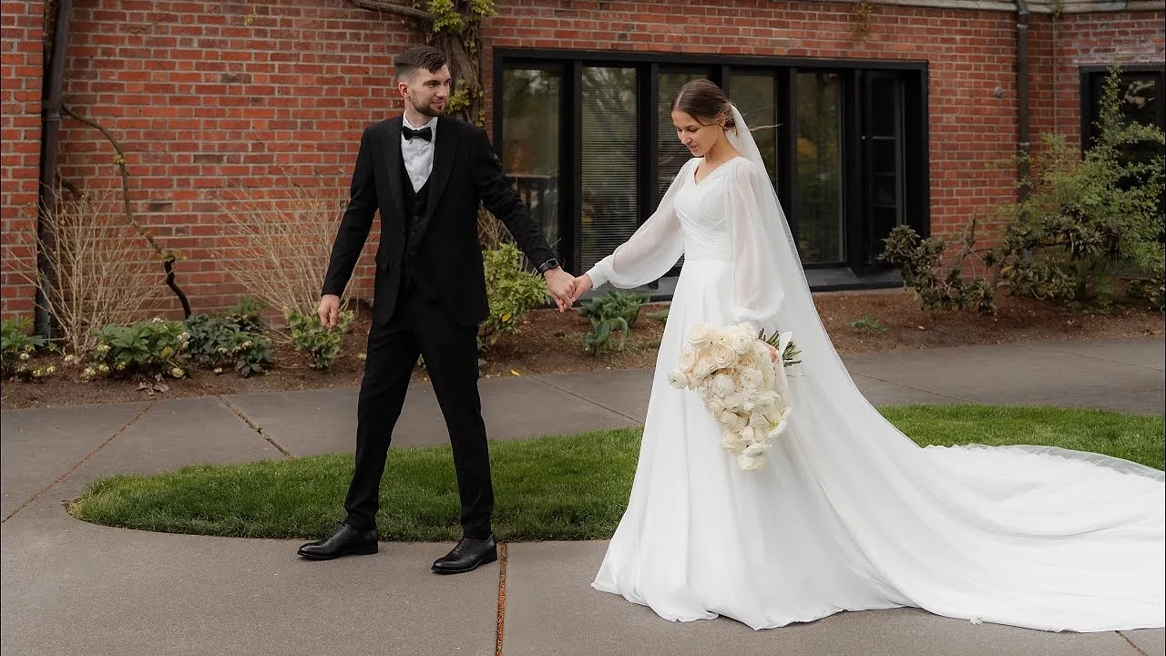 Bride and groom holding hands outside a brick building