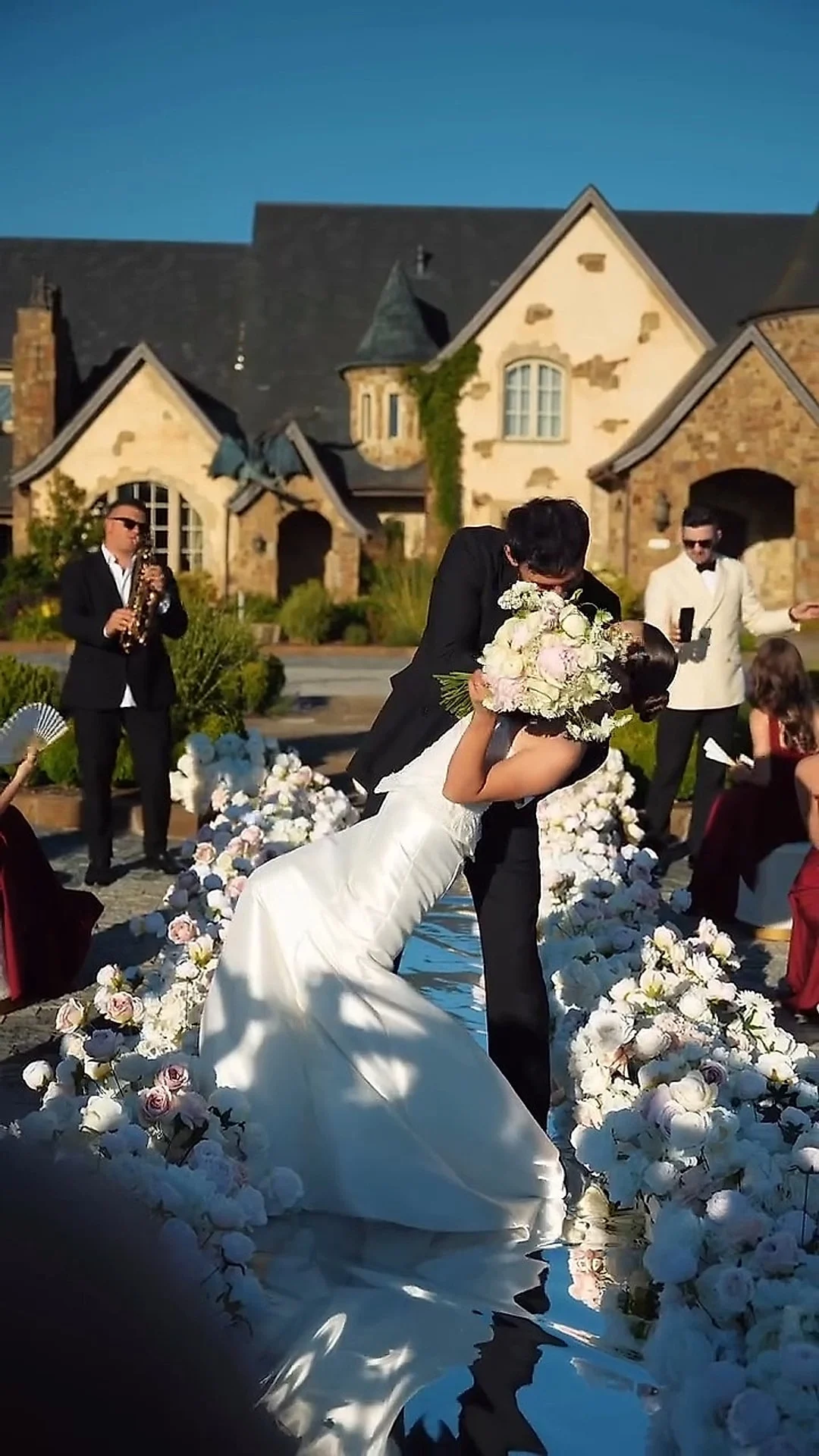Styled shoot at Chateau de Lis: groom dipping the bride for a kiss in a flower-lined courtyard
