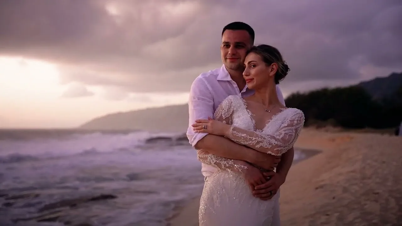 Couple embracing on a beach under a violet evening sky